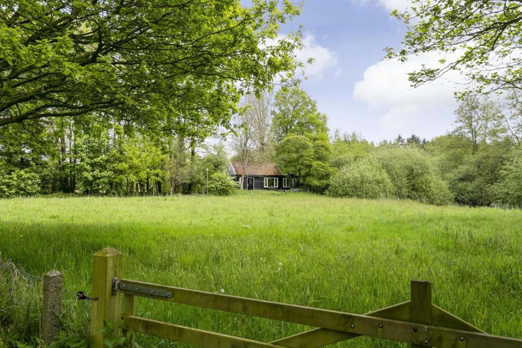 Ein altes Haus auf einem Feld mit einem Zaun in der Unterkunft Idyllic house with 360 view of nature in Dalfsen