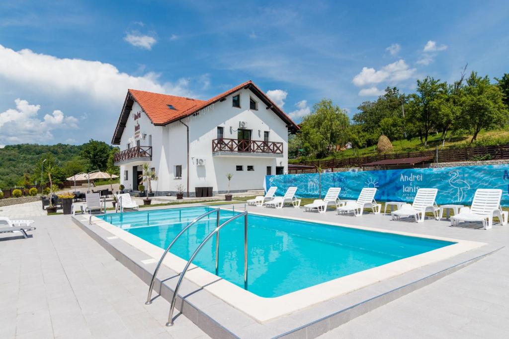 a villa with a swimming pool and a house at Agropensiunea Andrei & Ianis in Dăeşti