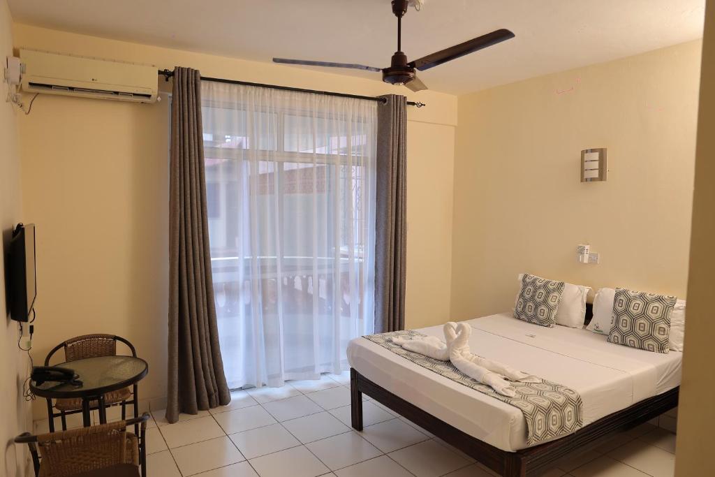 1 dormitorio con cama y ventana grande en Merry Villa Hotel & Apartments, en Mombasa