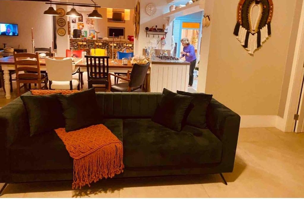 a living room with a green couch and a kitchen at Relaxar em Búzios Praia de Manguinhos 5 suítes in Búzios