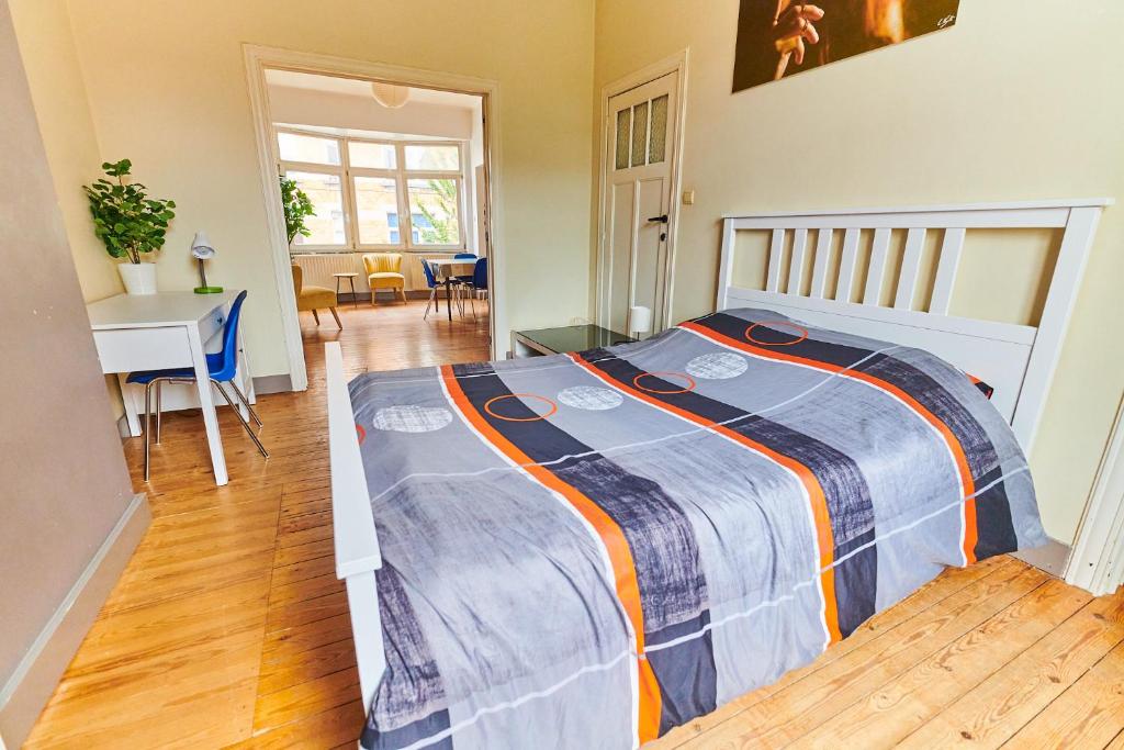 1 dormitorio con 1 cama con manta azul y naranja en César en Bruselas