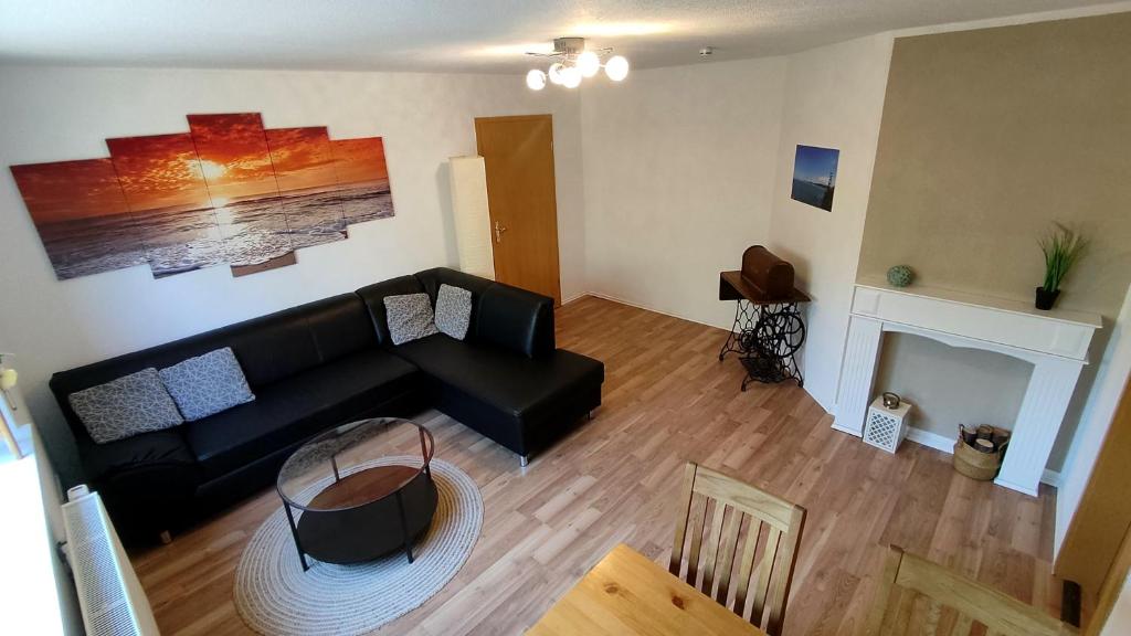 een woonkamer met een zwarte bank en een open haard bij *Gemütliche Ferienwohnung in perfekter Lage* in Wilsdruff