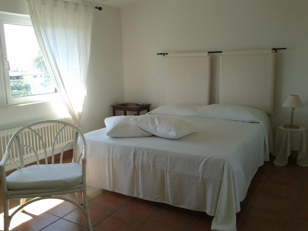a bedroom with two beds and a chair and a window at Casa Vacanze Giulienso in Ardea