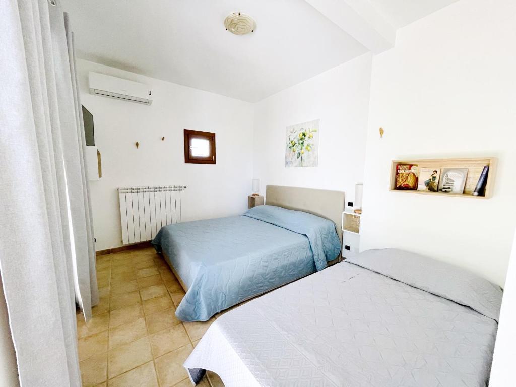 2 łóżka w pokoju z białymi ścianami w obiekcie Profumo di Limoni Vacation Rental w mieście Procida