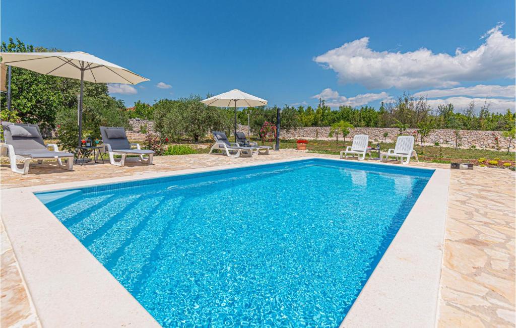 a swimming pool with chairs and umbrellas in a yard at Pet Friendly Home In Vinovo Donje With Kitchen in Donje Vinovo
