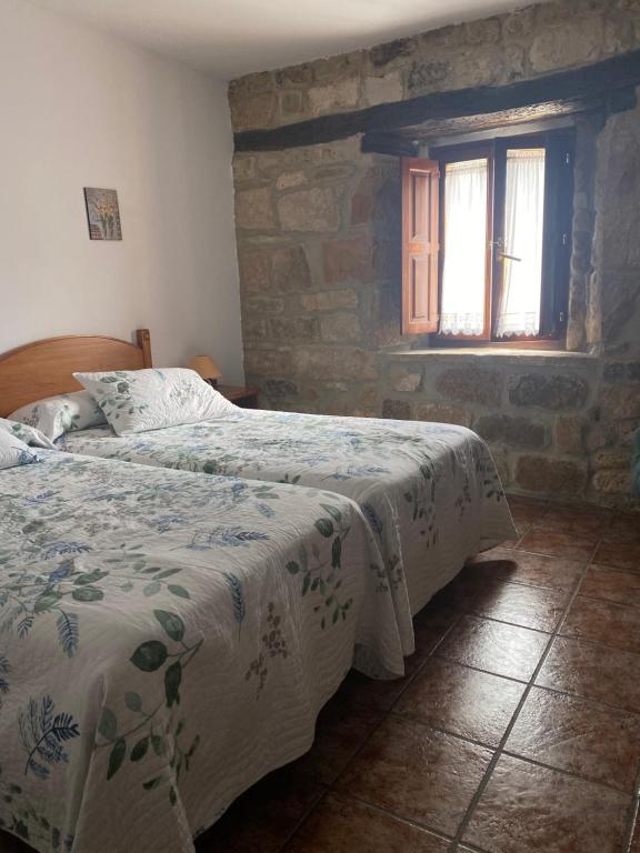 2 camas en un dormitorio con pared de piedra en Peñasalve, en Villamoñico