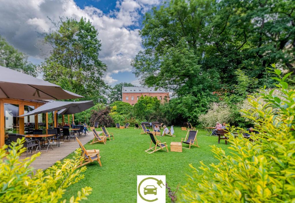 a park with chairs and tables on the grass at Hotel Yarden by Artery Hotels in Krakow