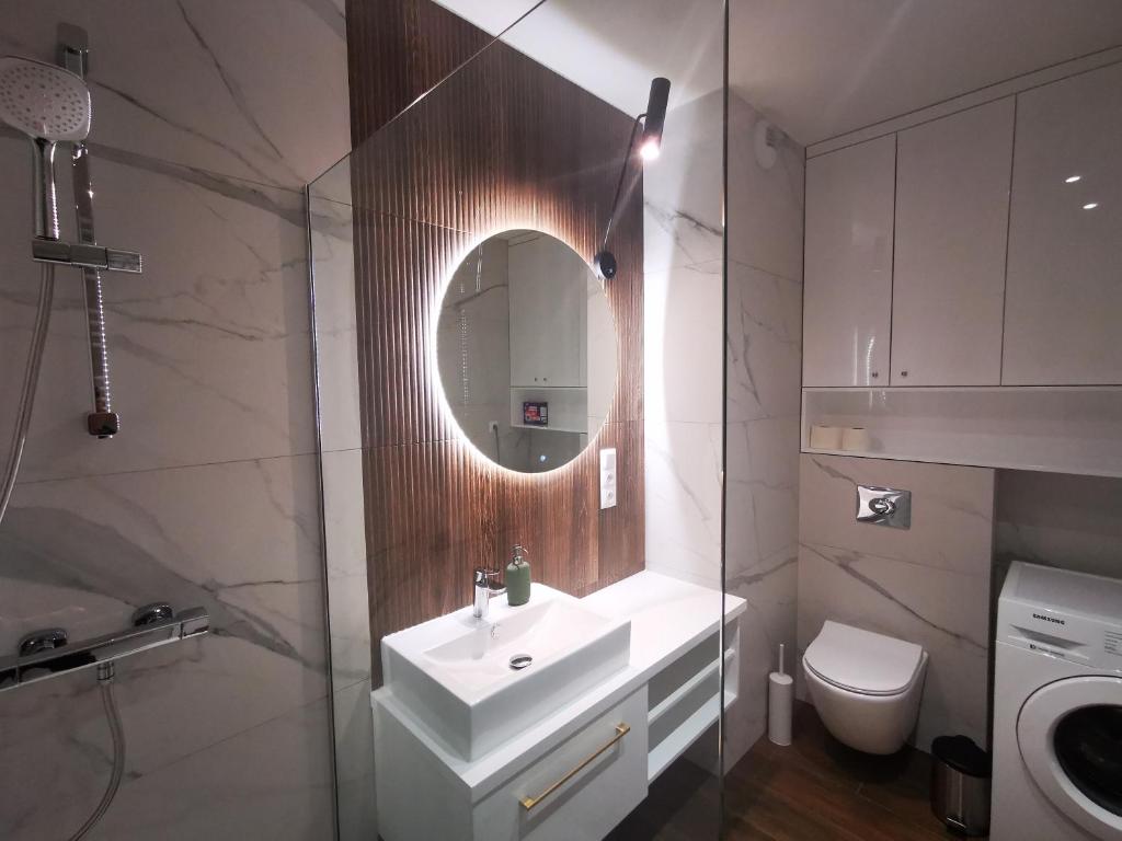 łazienka z umywalką, lustrem i toaletą w obiekcie Leśny Apartament Nad Zalewem No. 2 w Kielcach