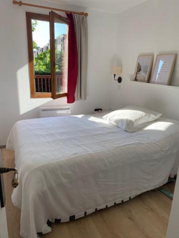 a white bed in a bedroom with a window at T3 neuf 5 pers Serre Chevalier La Salle les Alpes in La Salle Les Alpes