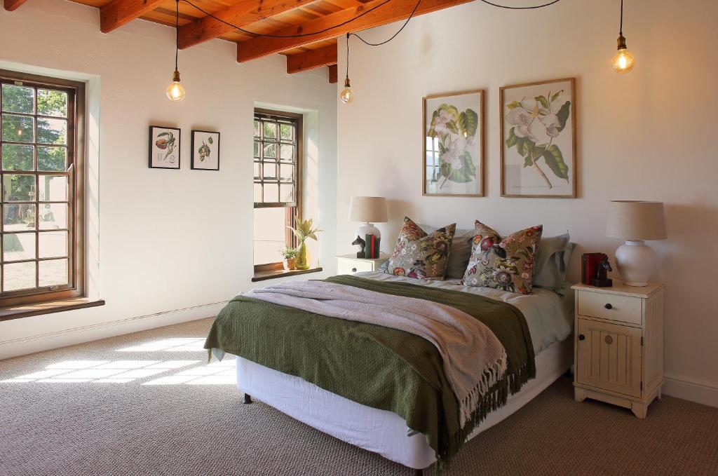a bedroom with a large bed and two windows at Jardin de la Ferme in Franschhoek