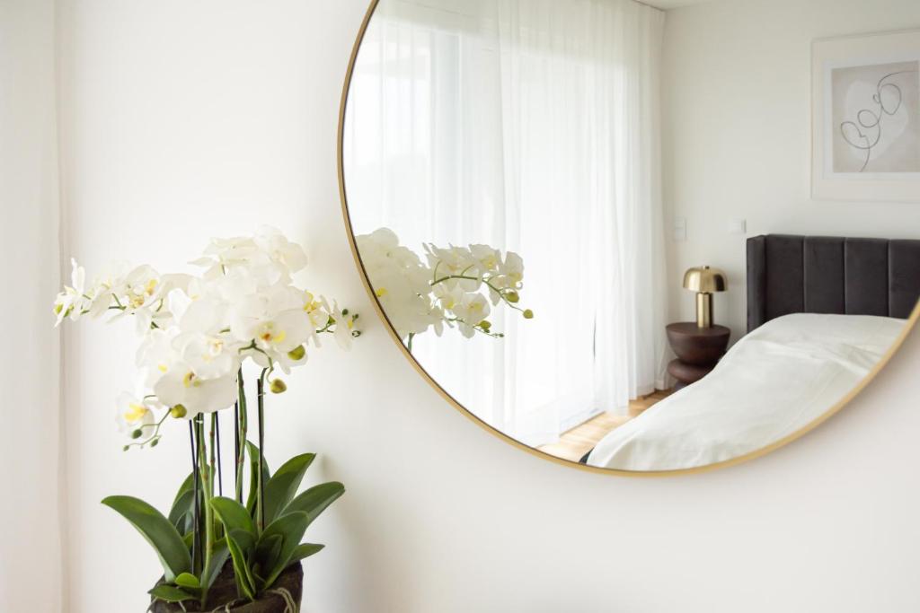 ein Schlafzimmer mit einem Spiegel und Blumen in einer Vase in der Unterkunft GRÜN & URBAN - direkt an der Therme - 15 Minuten ins Zentrum in Wien