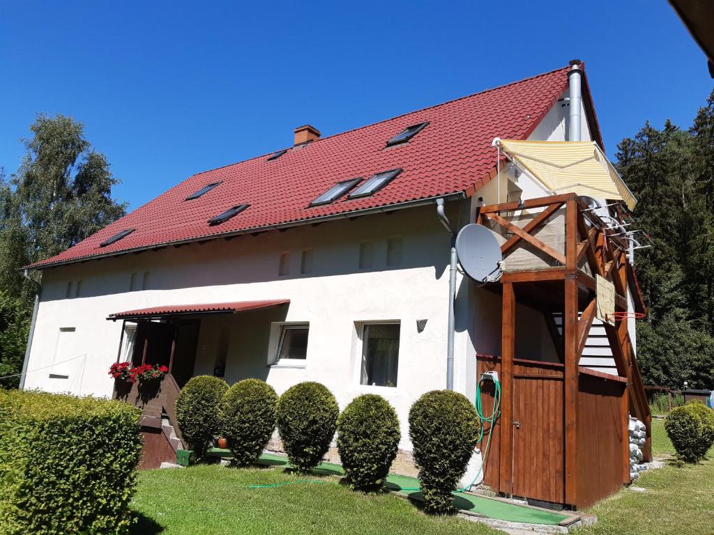 a white house with a red roof and some bushes at Apartament Zielony Zakątek in Sokołowsko