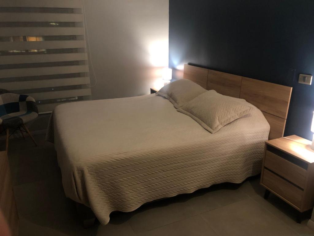 um quarto com uma grande cama branca e uma cabeceira em madeira em Departamento en el Corazon de Providencia em Santiago