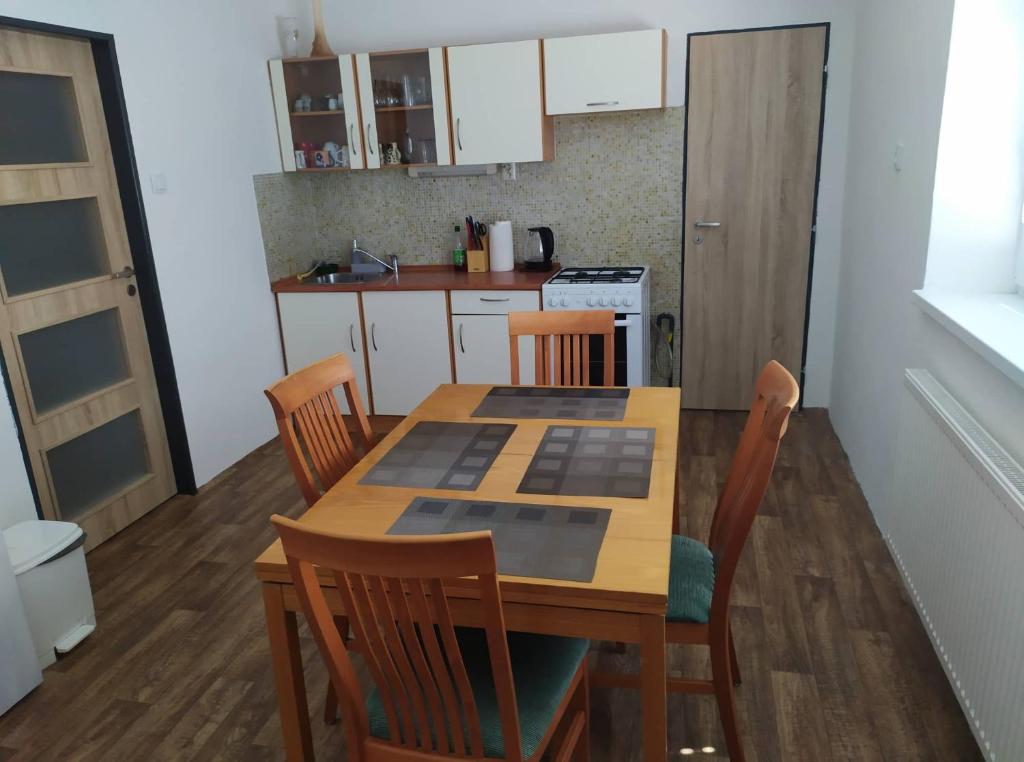 una cocina con una mesa de madera con sillas, una mesa y una mesa con sillas. en Apartmán Olomouc Nemilany en Olomouc
