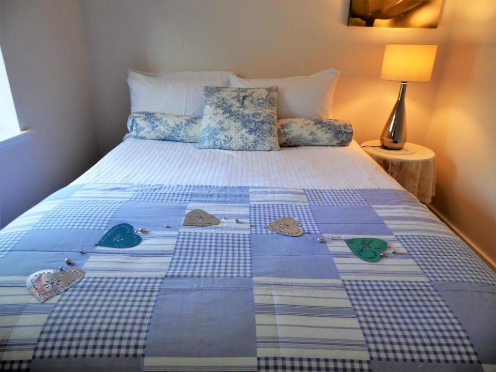 uma cama com uma colcha azul e branca em Signature - Campsie Cottage em Glasgow