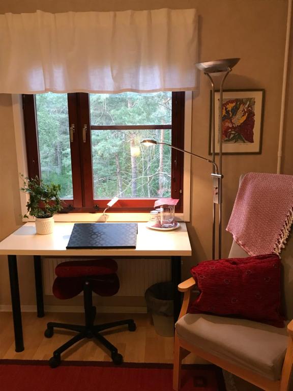 a desk with a laptop and a chair in front of a window at Anikos in Uppsala