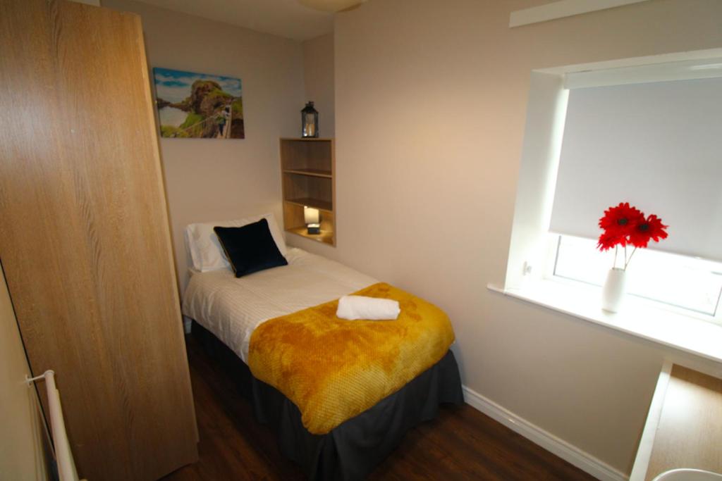 a small bedroom with a bed and a window at Beulah Guest House in Portrush