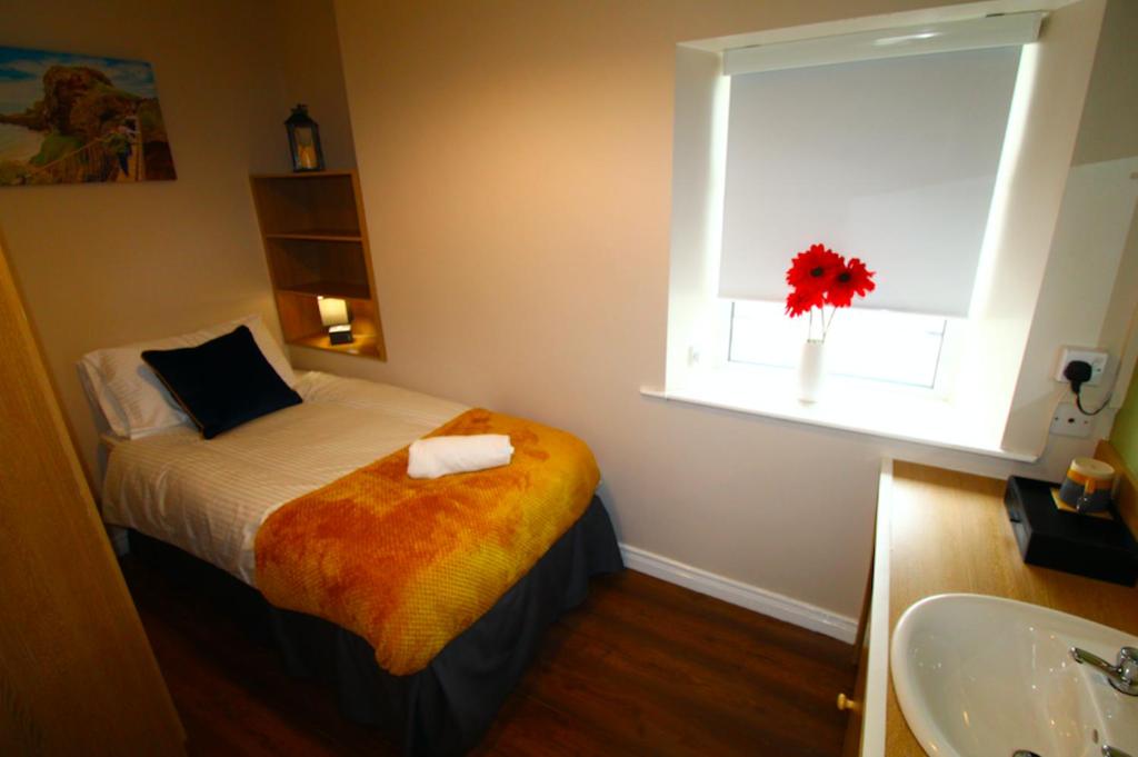 a bedroom with a bed and a window and a sink at Beulah Guest House in Portrush