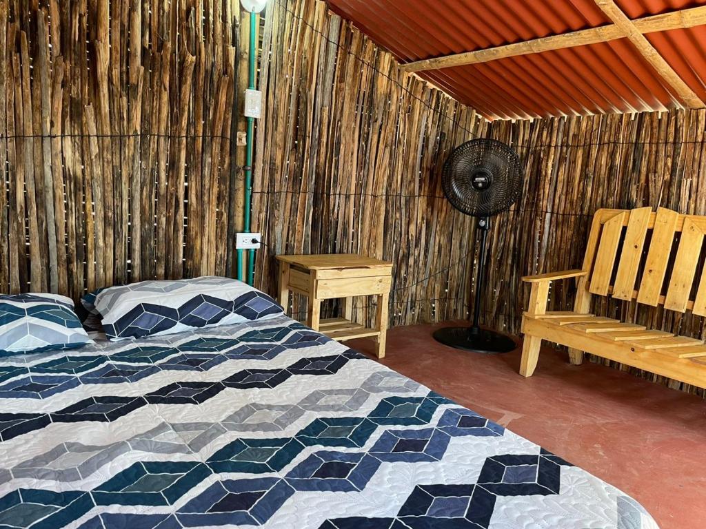 um quarto com uma cama, um ventilador e um banco em Hostal Playa Perdida em Ríohacha