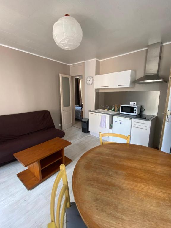 eine Küche und ein Wohnzimmer mit einem Tisch und einem Sofa in der Unterkunft Joli appartement entier T2 centre ville de Cherbourg in Cherbourg en Cotentin