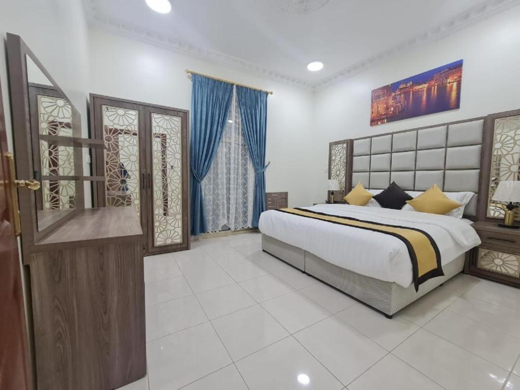 a bedroom with a large bed with blue curtains at الزمرد للشقق المخدومة in Al Khobar