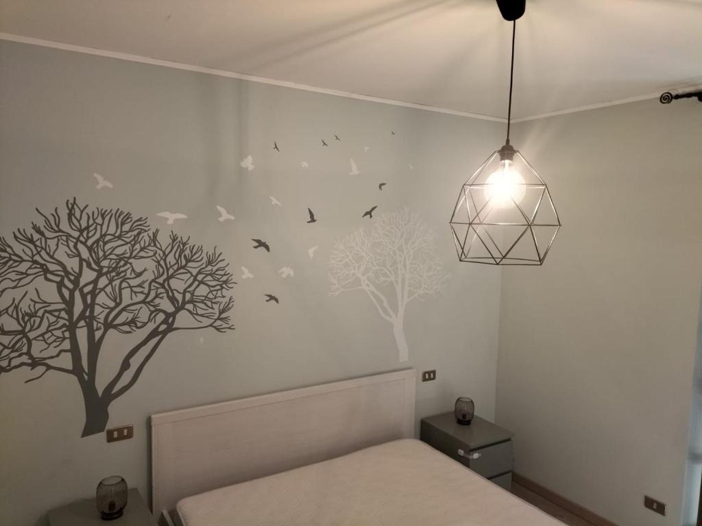 sypialnia z łóżkiem i drzewami na ścianie w obiekcie Casa Rina w mieście Nesso