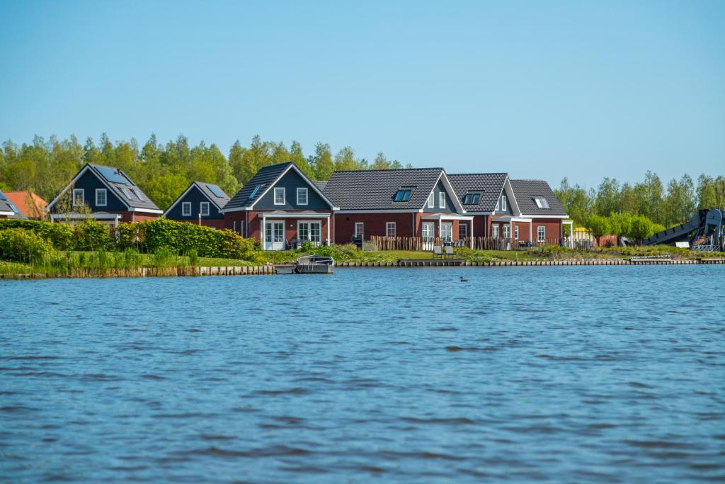 uma fila de casas ao lado de um grande corpo de água em Europarcs Ijsselmeer em Medemblik