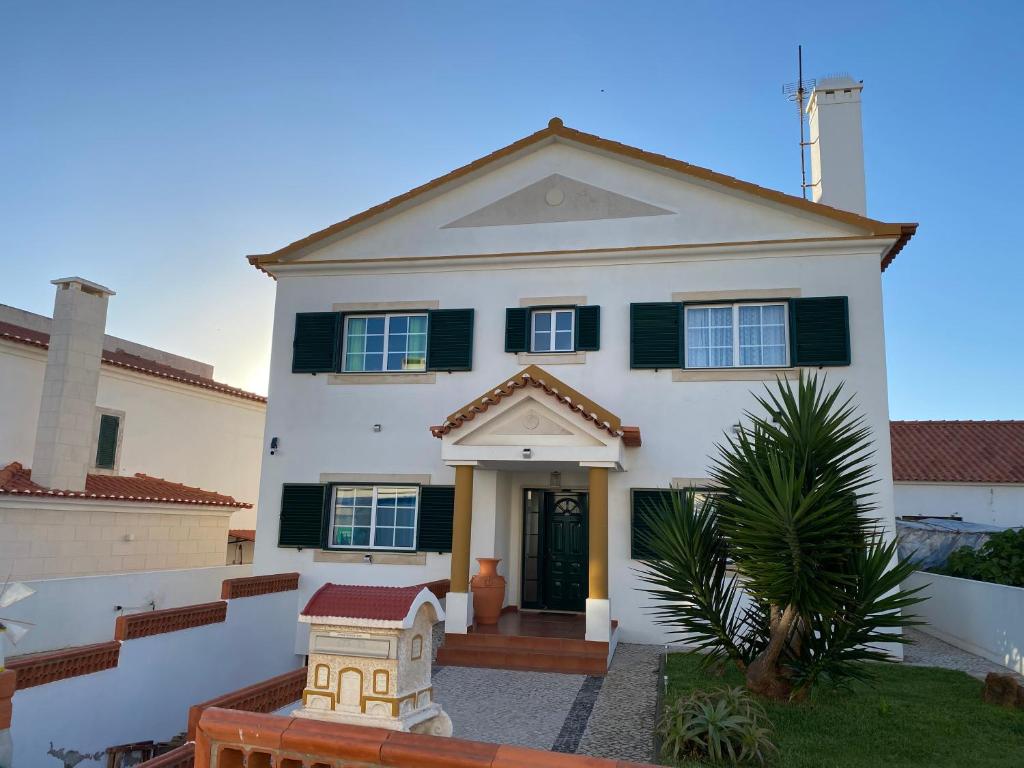 a white house with black shutters at Villa Kethellen in Porto Covo