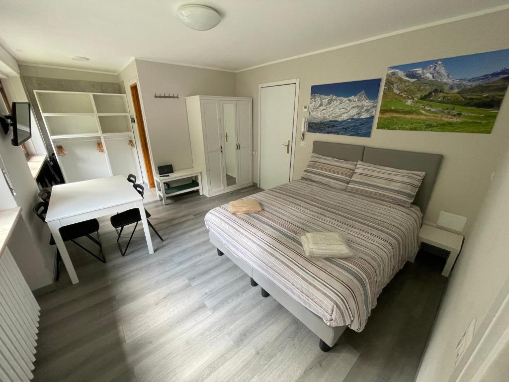 een slaapkamer met een bed, een bureau en een tafel bij Appartamento Funivie CIR 0140 in Breuil-Cervinia