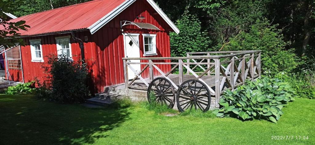 a red barn with a wooden cart in the grass at Lillstugan i idyllisk lugn miljö nära Hällungen, Stenungsund in Ucklum