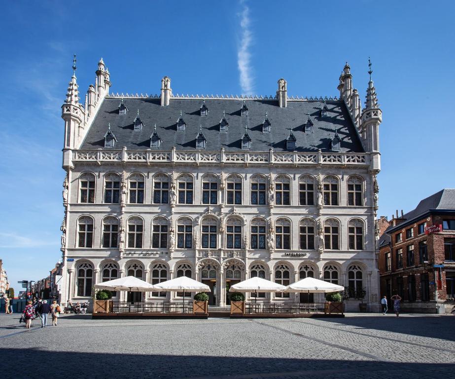 un grand bâtiment blanc avec des parasols en face de celui-ci dans l'établissement The Fourth - Tafelrond, à Louvain