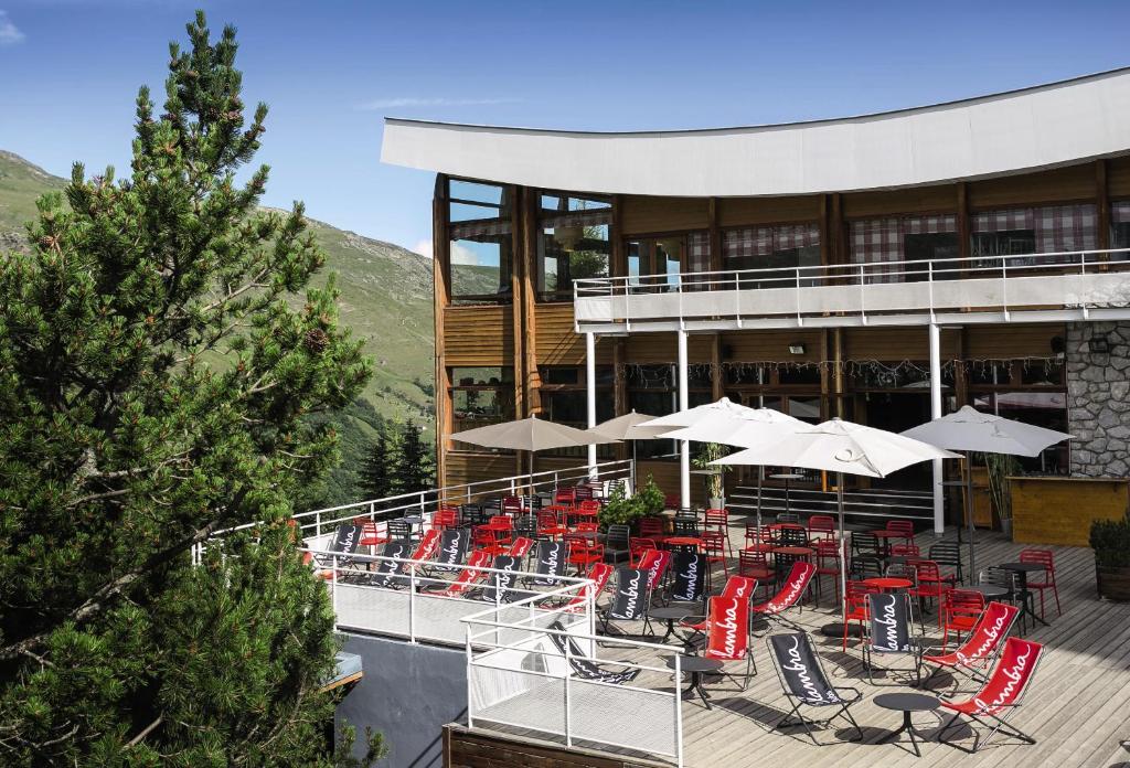 una terraza con sillas rojas y mesas en un edificio en Belambra Clubs Les Menuires - Neige Et Ciel, en Les Menuires