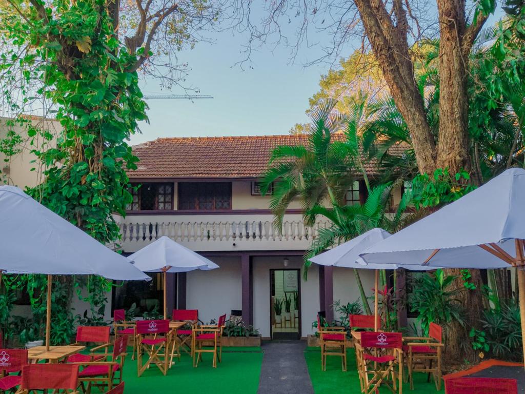 un patio con mesas, sillas y sombrillas en El Nogal Casa Hotel, en Asunción