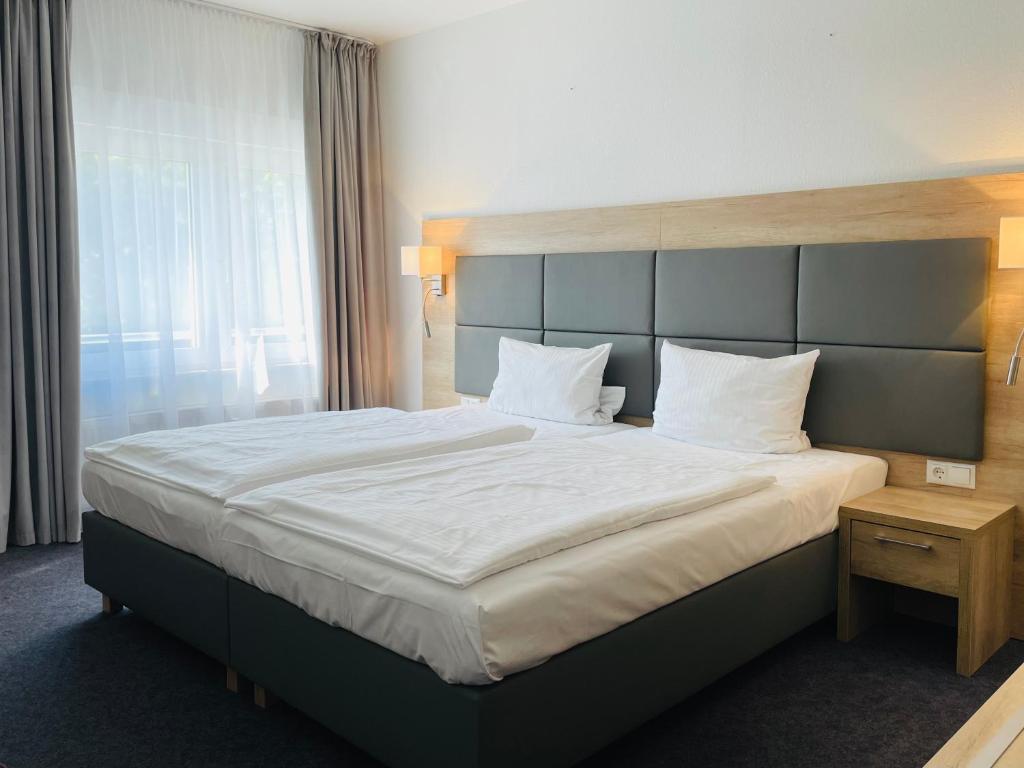 a hotel room with a large bed with white sheets at Hotel Esmer in Lollar