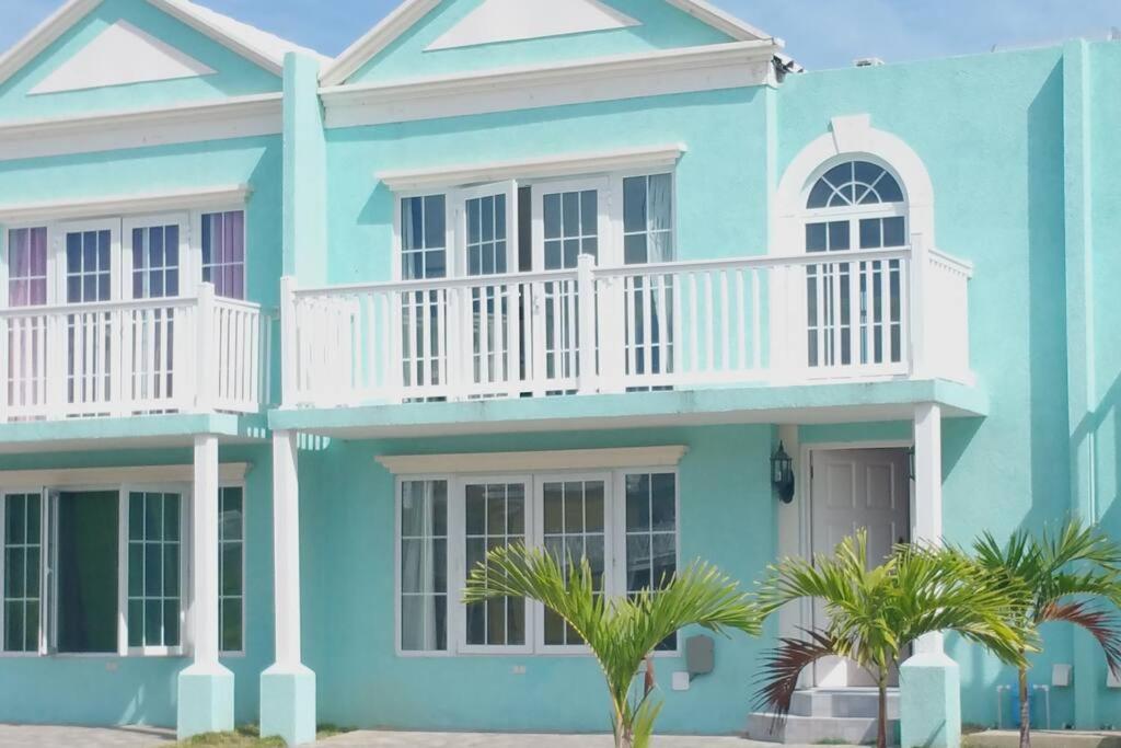 una casa blu con un balcone bianco e palme di Townhouse by The Bay, Little Bay Country Club ,Negril a Orange Bay