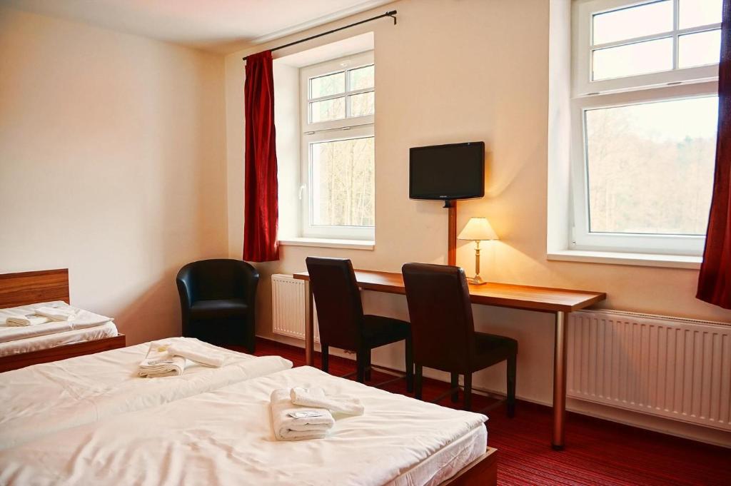 Pokój hotelowy z 2 łóżkami i biurkiem z krzesłami w obiekcie Restaurace a penzion Zděná Bouda w mieście Hradec Králové