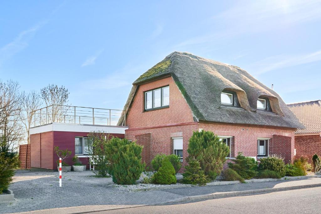 a large red brick house with a thatched roof at Seestern in Nordstrand