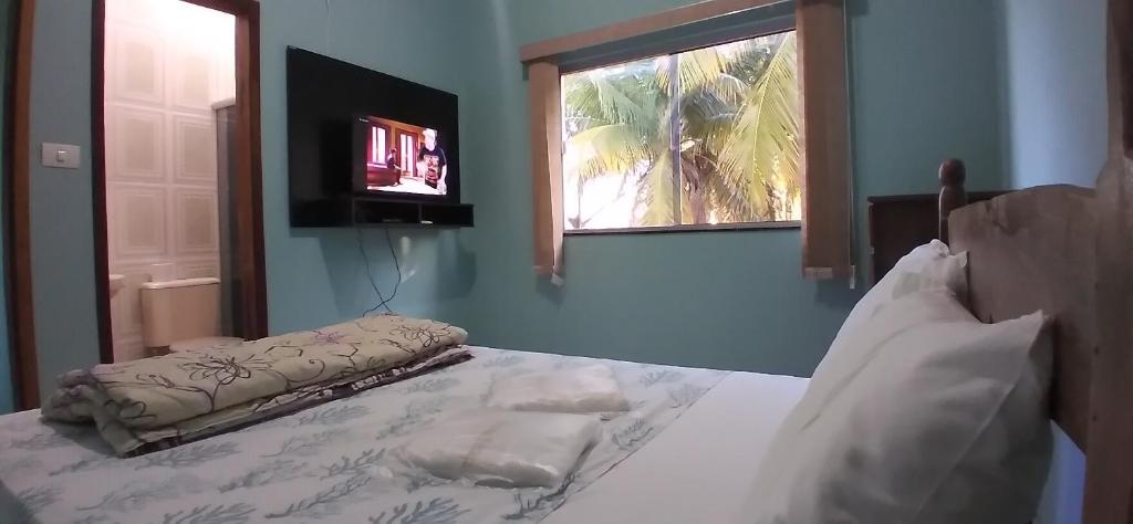 una camera da letto con un letto, una finestra e una televisione di Pousada Peruaçu & Restaurante a Fabião