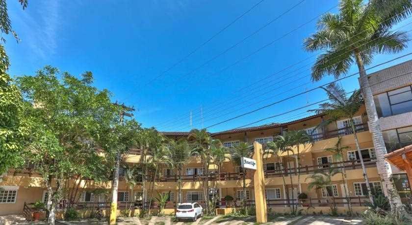 un grand bâtiment avec des palmiers devant dans l'établissement FLAT AMARILIS RIVIERA DE SÃO LOURENÇO, à Bertioga