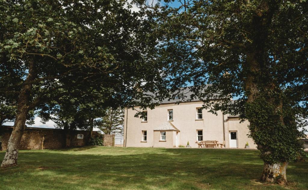 una gran casa blanca con árboles delante de ella en The Herdsman's House en Thurso