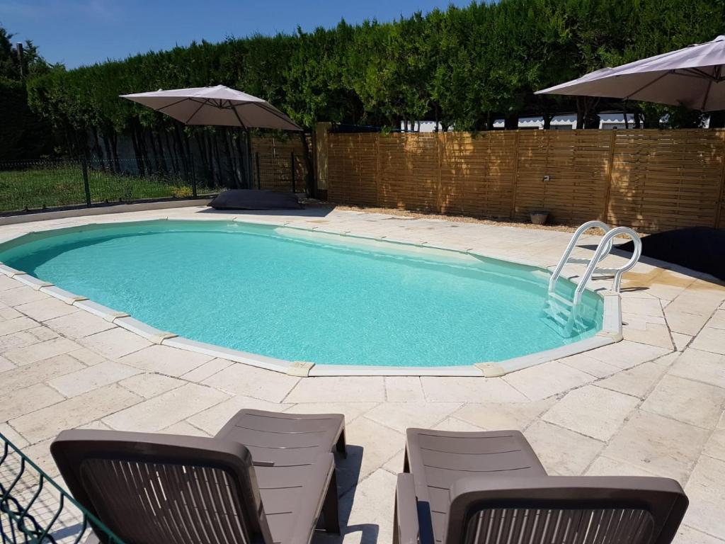 uma piscina com duas cadeiras e um guarda-sol em LUBERON EN PROVENCE GITE 3 CHAMBRES 100 m2 avec PISCINE PRIVEE em Cheval-Blanc