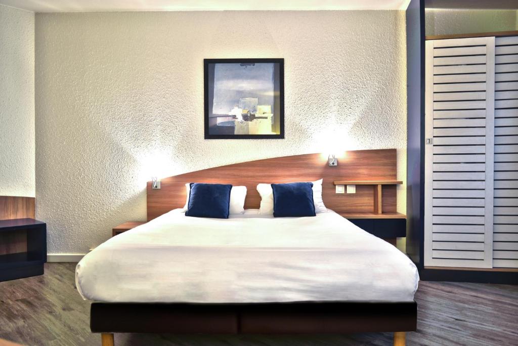 a bedroom with a large bed with blue pillows at Art Hotel Paris Est in Pantin