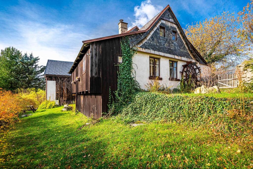 una vieja casa con hiedra creciendo a su lado en Čertův mlýn - pohádková chalupa - Jizerské hory, en Weissbach