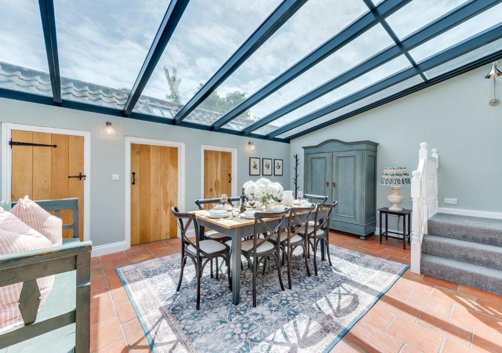 a conservatory with a dining room with a table and chairs at Sand Stone Cottage in Northrepps
