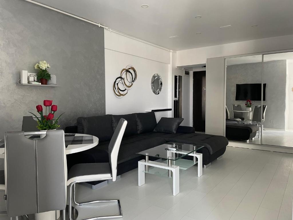 a living room with a black couch and a table at Luxury Westpark 2-Room Apartment Lakeview W5 in Bucharest