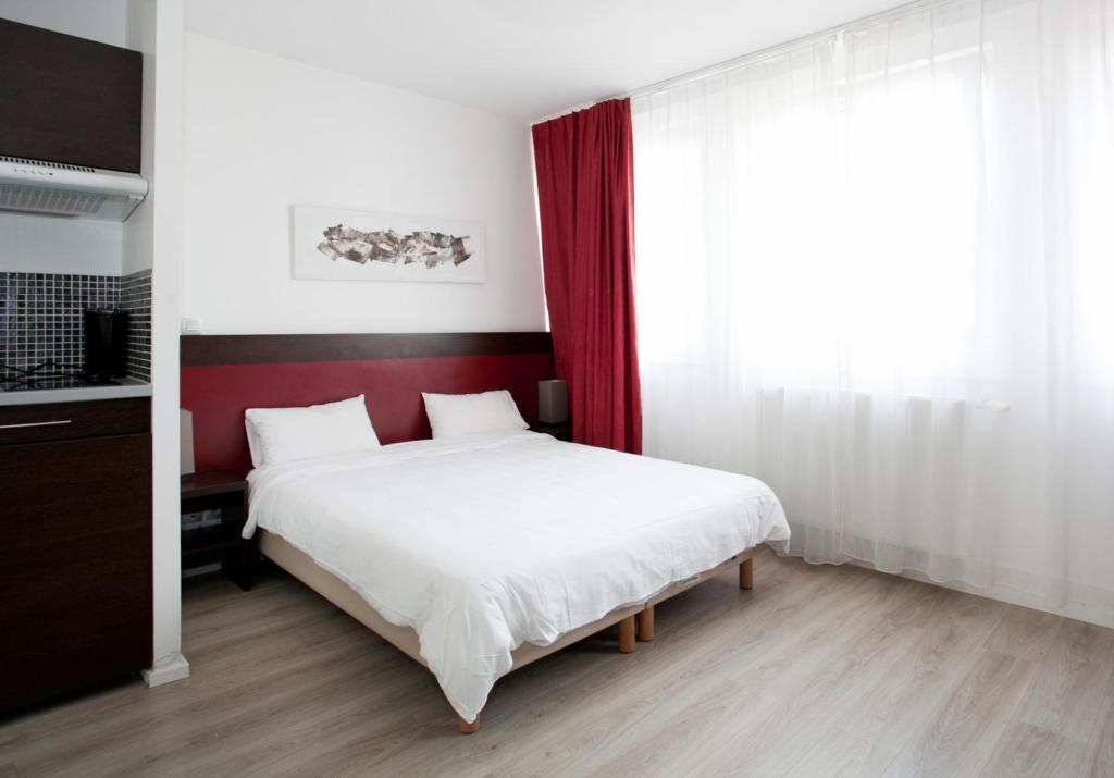 1 dormitorio con 1 cama blanca grande y cabecero rojo en Residhotel Lille Vauban en Lille