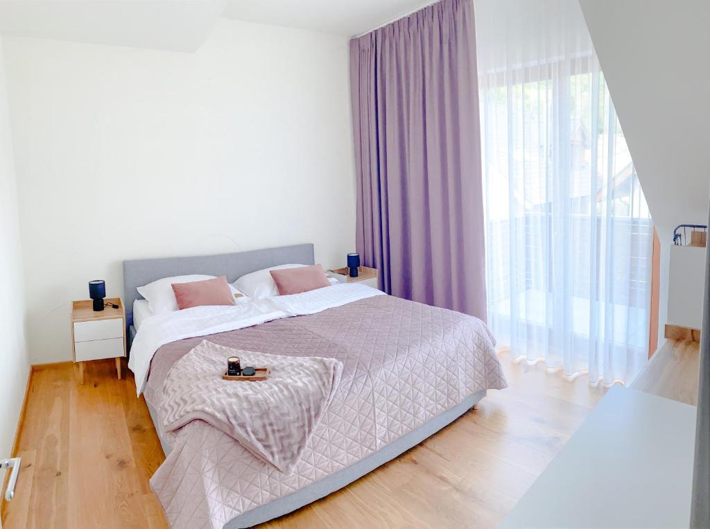 um quarto branco com uma cama grande e almofadas cor-de-rosa em Superb Mýto Apartment em Mýto pod Ďumbierom