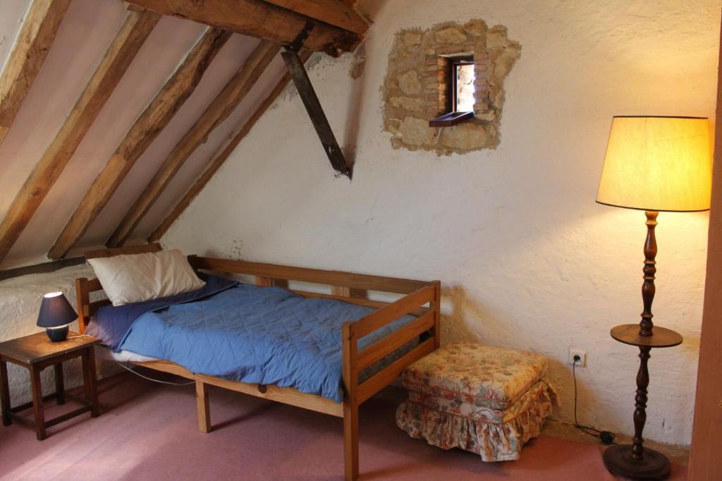 ein Schlafzimmer mit einem Bett und einer Lampe in einem Zimmer in der Unterkunft Grand gîte de campagne capacité jusqu'à 10 personnes in Chantenay-Saint-Imbert