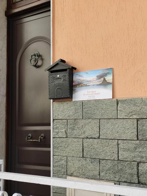 Skrzynka na listy siedząca na murze obok drzwi w obiekcie La Casa In Riva Al Mare w mieście Aci Castello