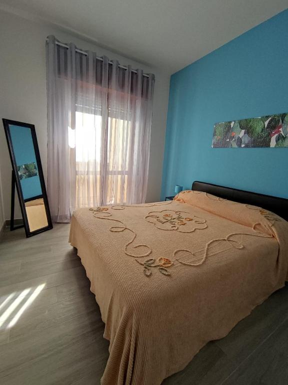 sypialnia z łóżkiem z niebieskimi ścianami i oknem w obiekcie La Casa In Riva Al Mare w mieście Aci Castello